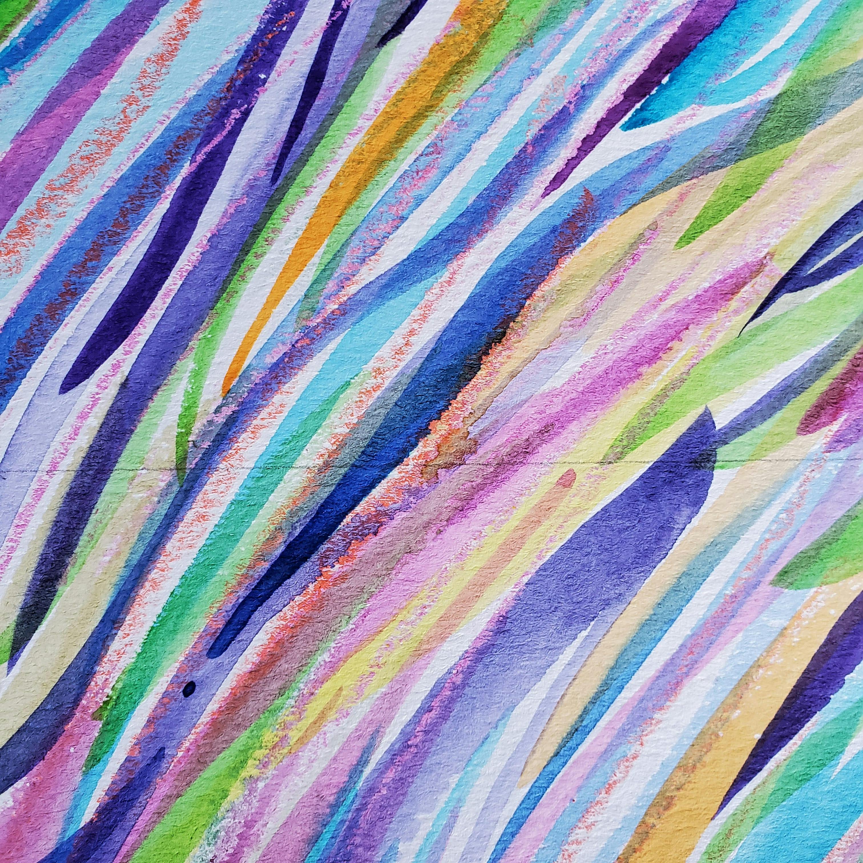 Close-up photo of a small mixed media painting, with swipes of blue-violet, light green, yellow-orange, and other colors.