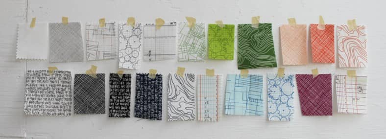 21 fabric swatches taped to a white wall. The fabrics were designed by Carolyn Friedlander for her Architextures fabric line. Click image to view source.
