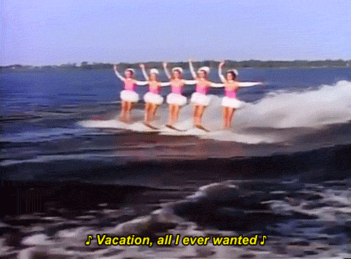 Animated GIF of five women in pink and white outfits waterskiing. At the bottom of the image the subtitle reads "Vacation, all I ever wanted" from the Go-Go's song.