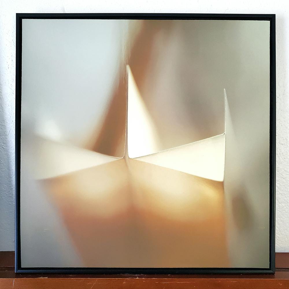 Photo of framed hotel art. The image is an abstract view of folded paper.