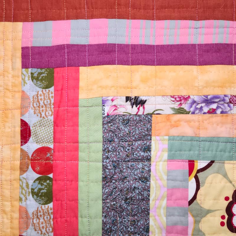 Detail view of Boho Baby. This view shows one of the central squares surrounded by strips of increasing length. Both machine stitches and hand stitches are visible.