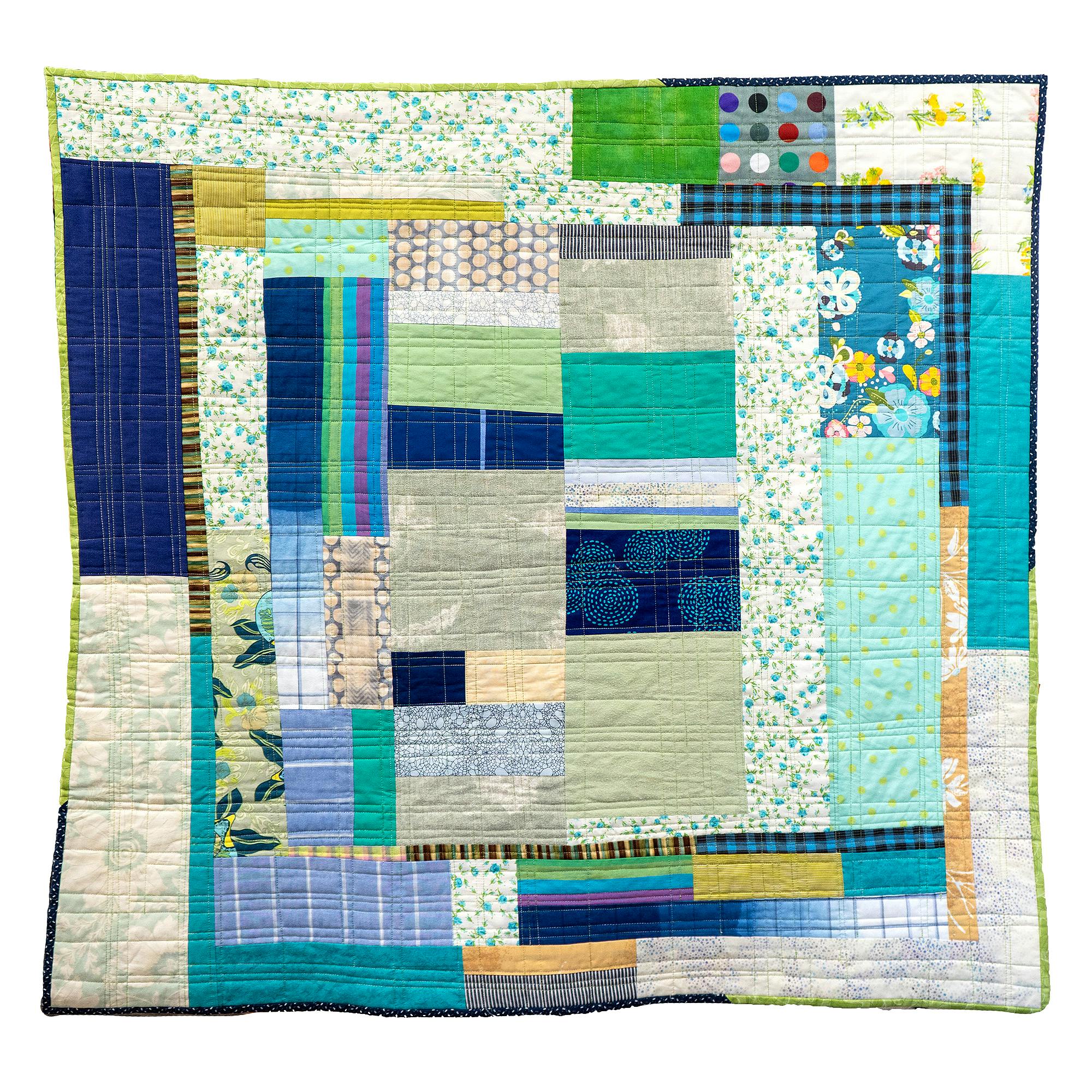 Photo of a patchwork quilt with fabrics in green, blue, white, and other colors.