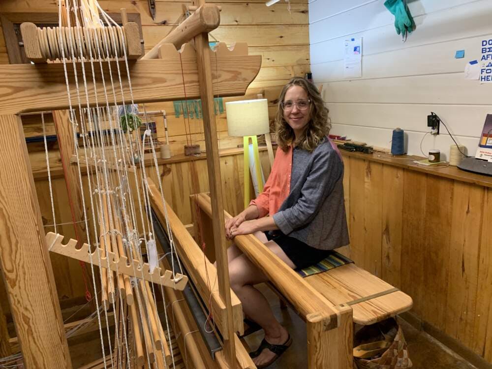 Weaver Christine Novotny sits at the loom in her workshop. Photo credit Jon Kalish.