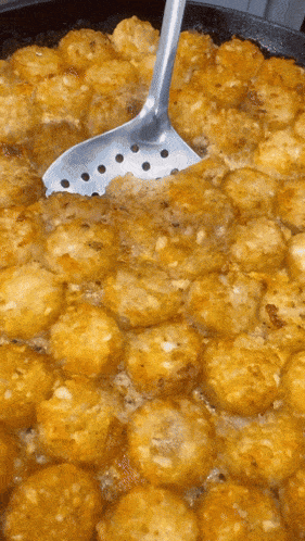 Animated image of a large spoon dipping into a cauldron of tater tot casserole and placing the food on a plate. 