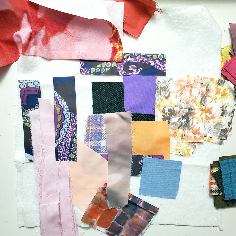 Photo of fabric scraps in various colors placed on a white piece of quilt batting.