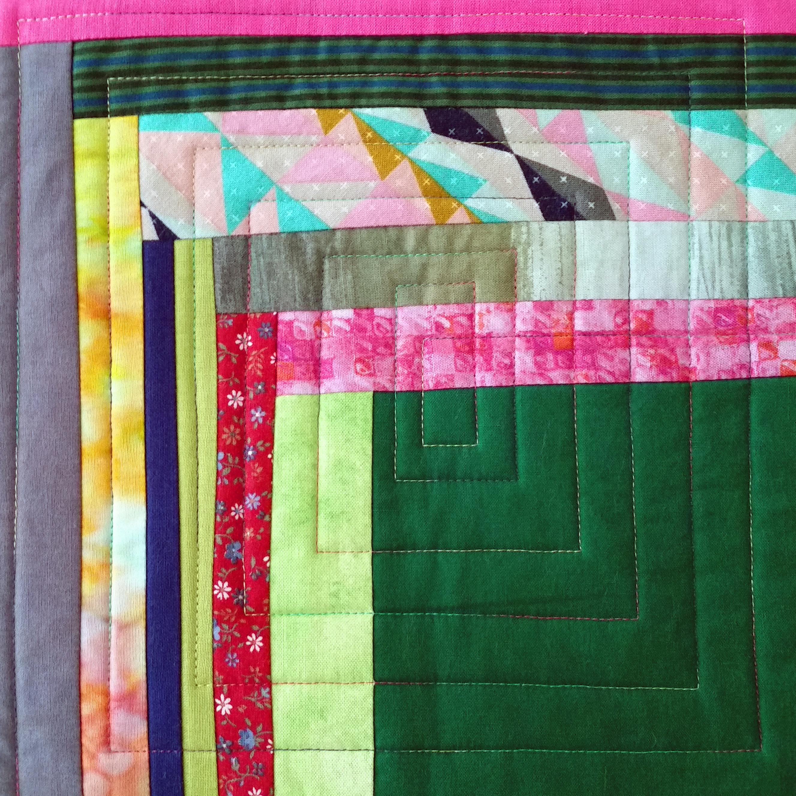 Closeup photo of a quilt block, with fabrics in green, pink, grey, and other colors.
