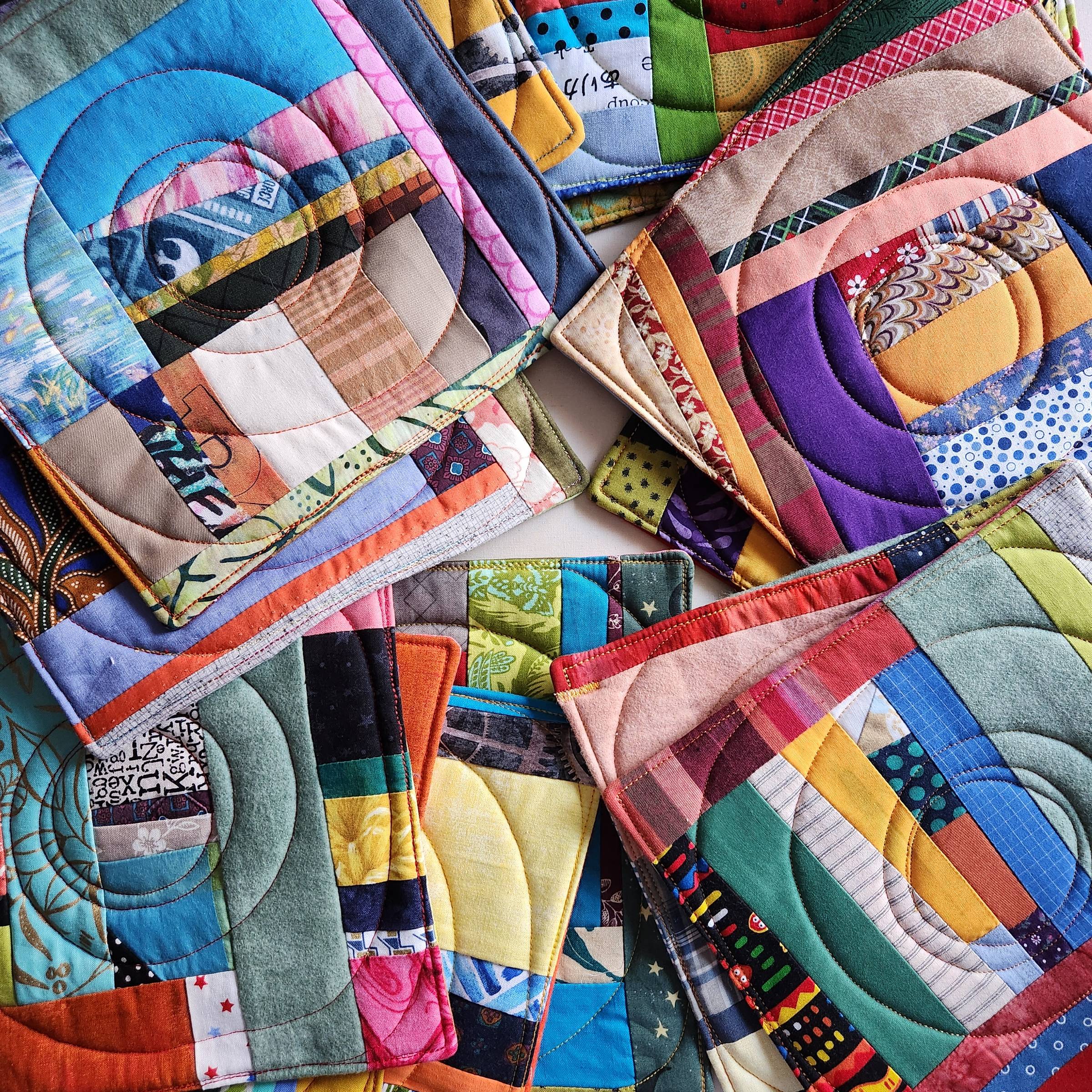 Photo of a pile of Sarah's patchwork potholders. These mini-quilts use fabrics in every color. Click on the image to view Sarah's online store.