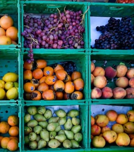 Assortment of fresh fruits and vegetables in green crates.