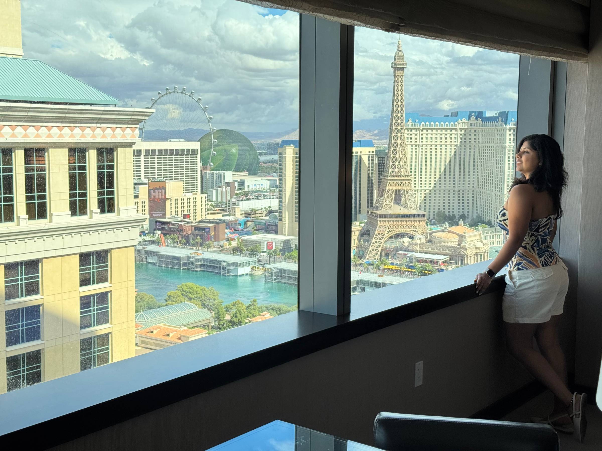 Woman looking outside her Vegas room at Bellagio fountains and the Vegas strip