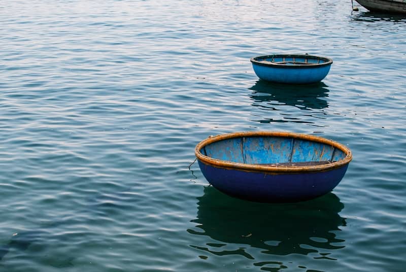Two round blue boats float on calm water.