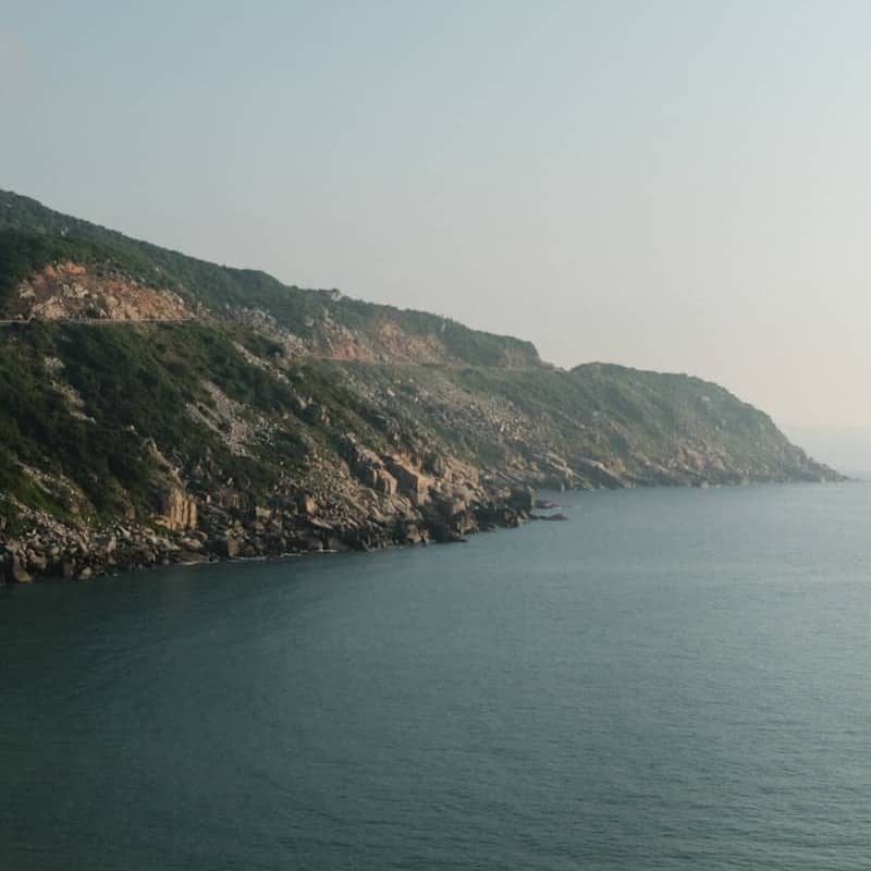 Coastal mountains meet the calm, blue ocean.