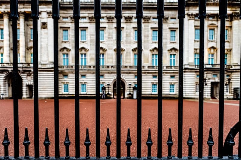 A luxury mansion, seen from behind a metallic gate.