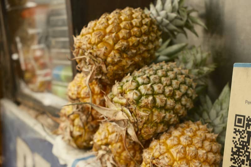 A stack of fresh pineapples with spiky green leaves on a market stall