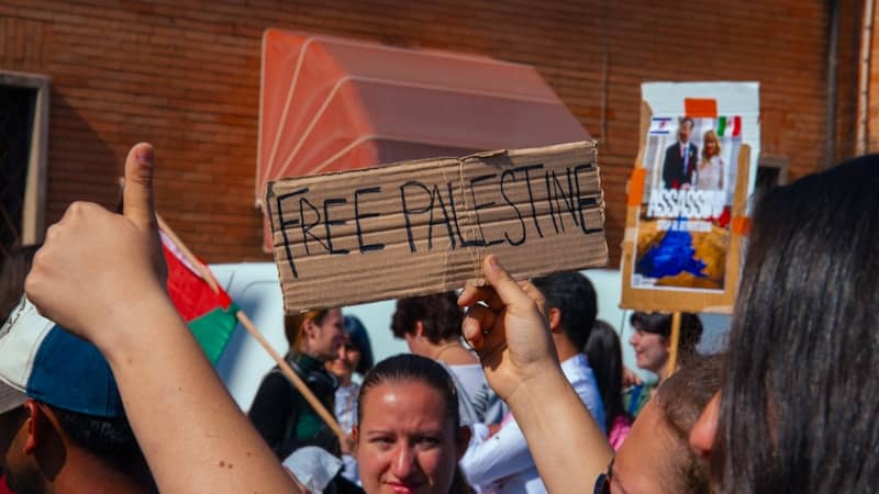 Protesters hold signs at a rally for free palestine.