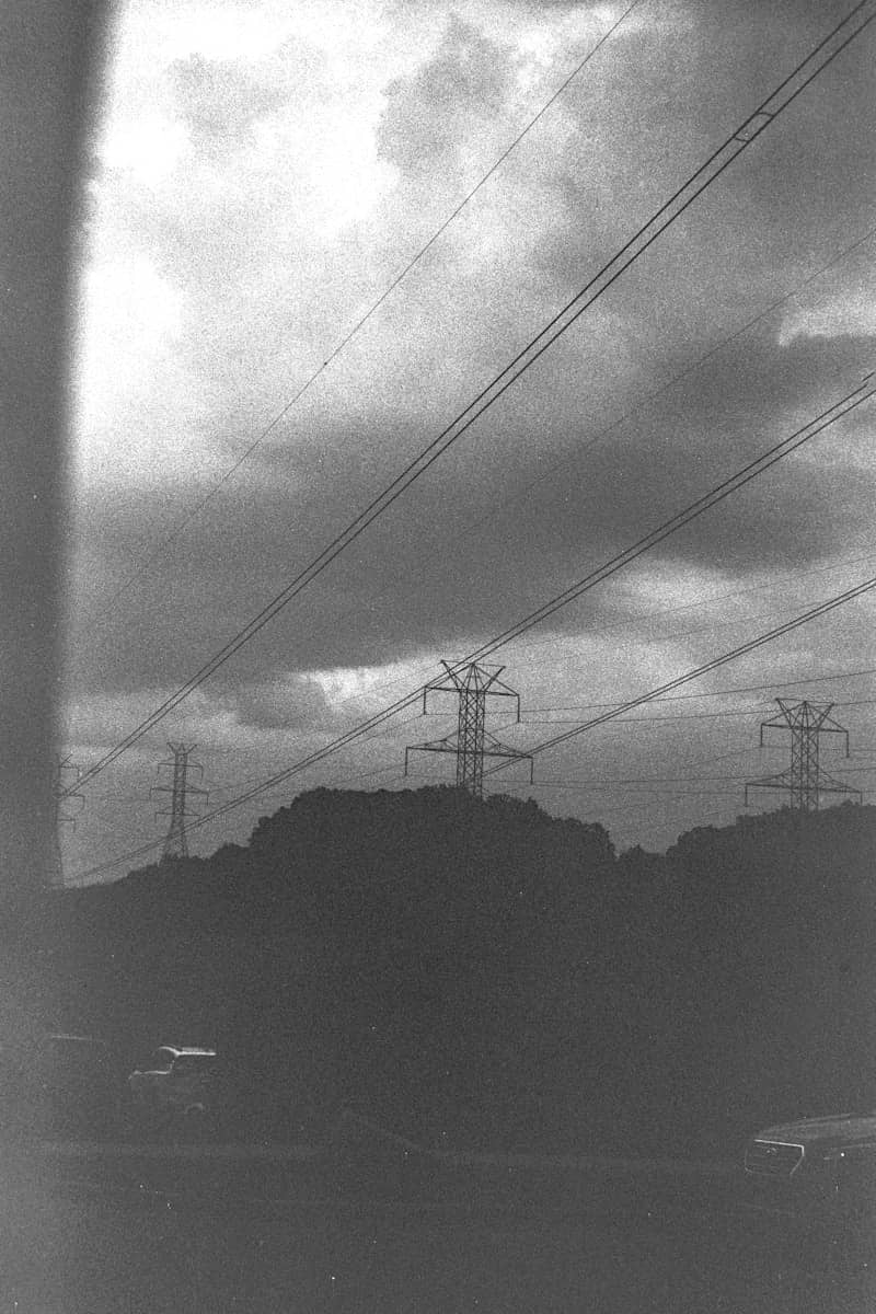 Transmission towers and power lines against a dark, cloudy sky.