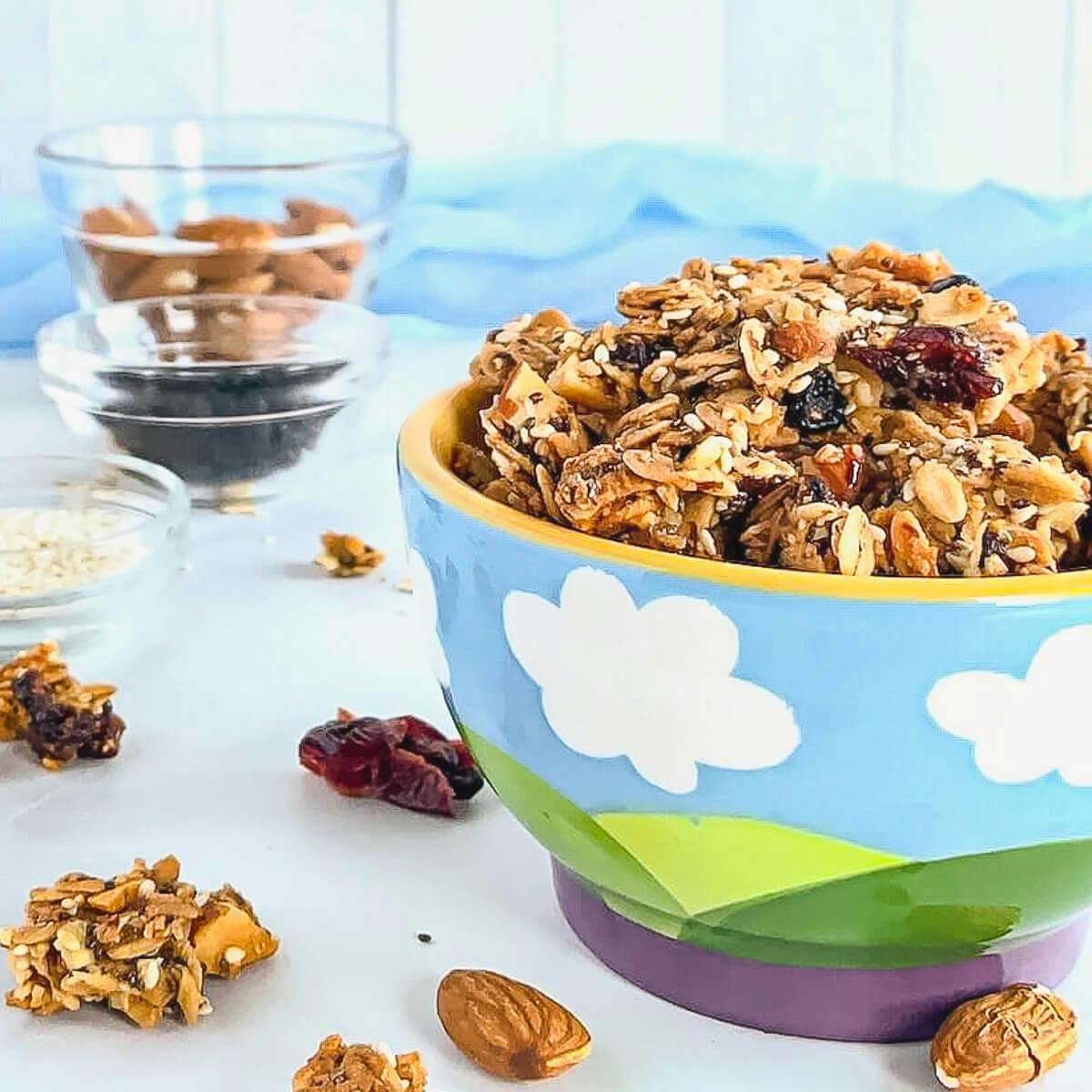 Granola in a bowl next to ingredients portioned into glass bowls.