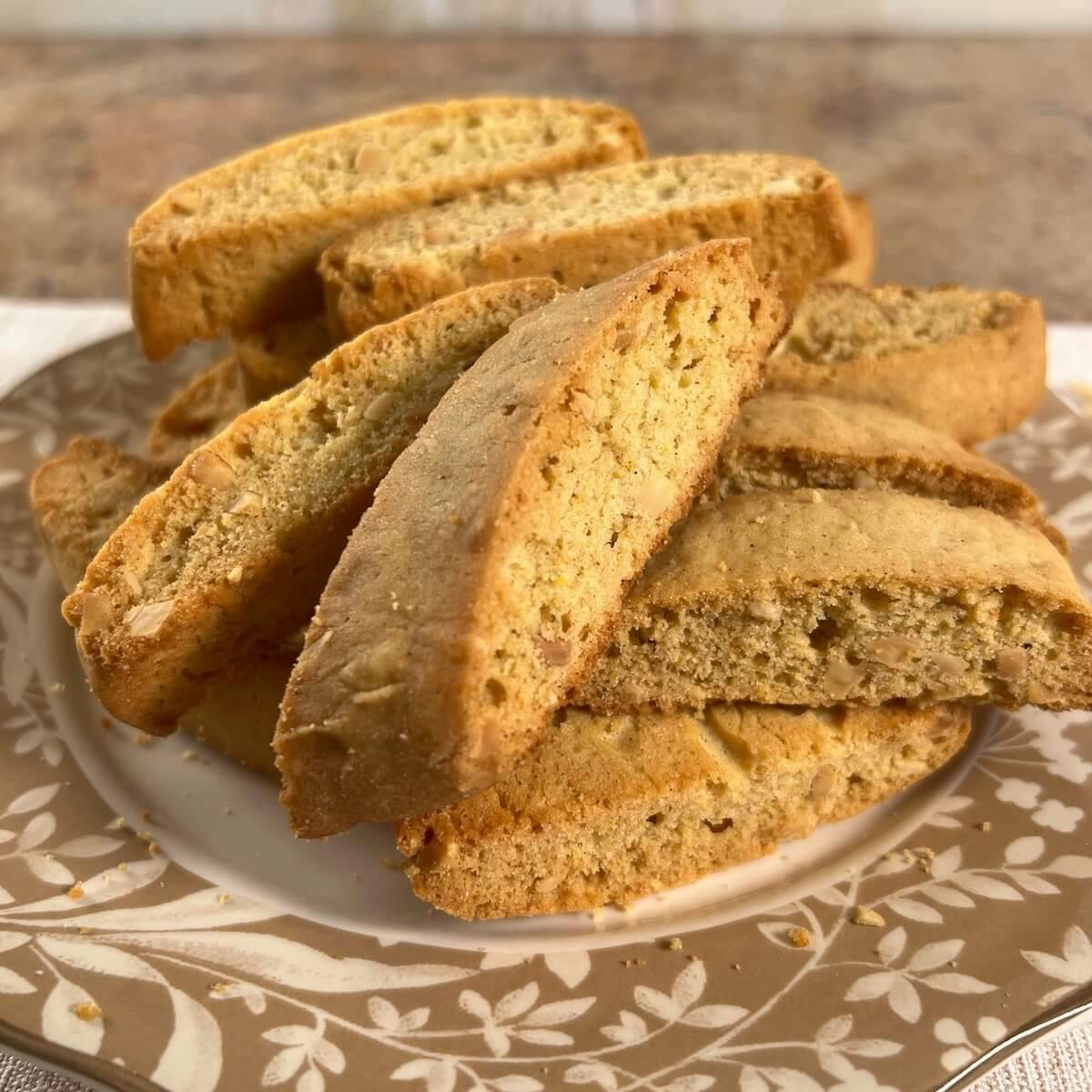 Mandel bread piled onto a white plate with a brown flowered edging.