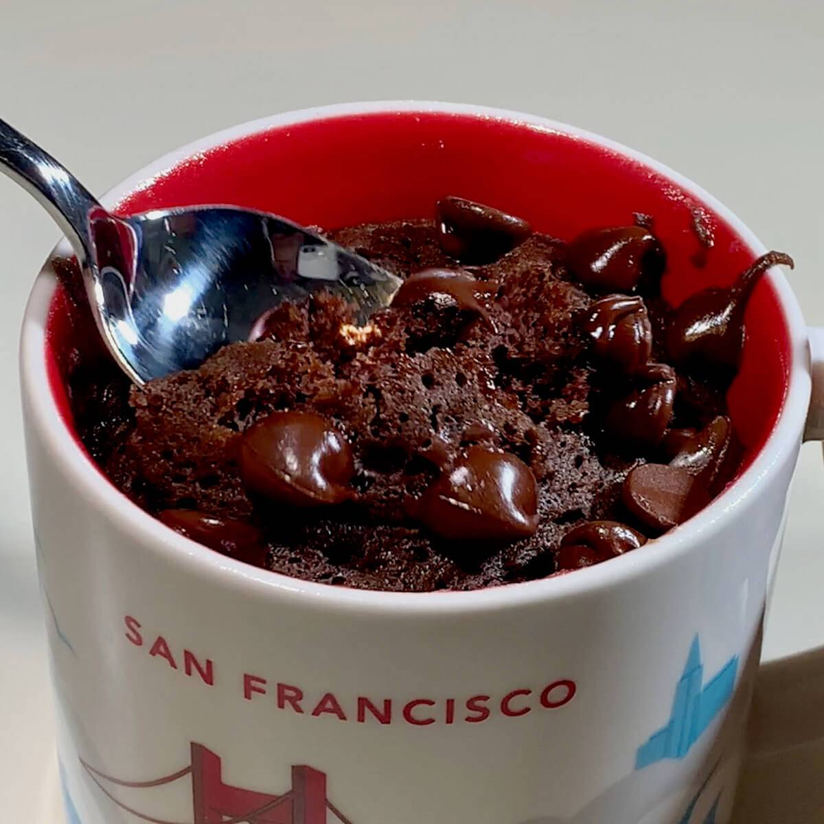 Chocolate mug cake with spoon lifting cake.