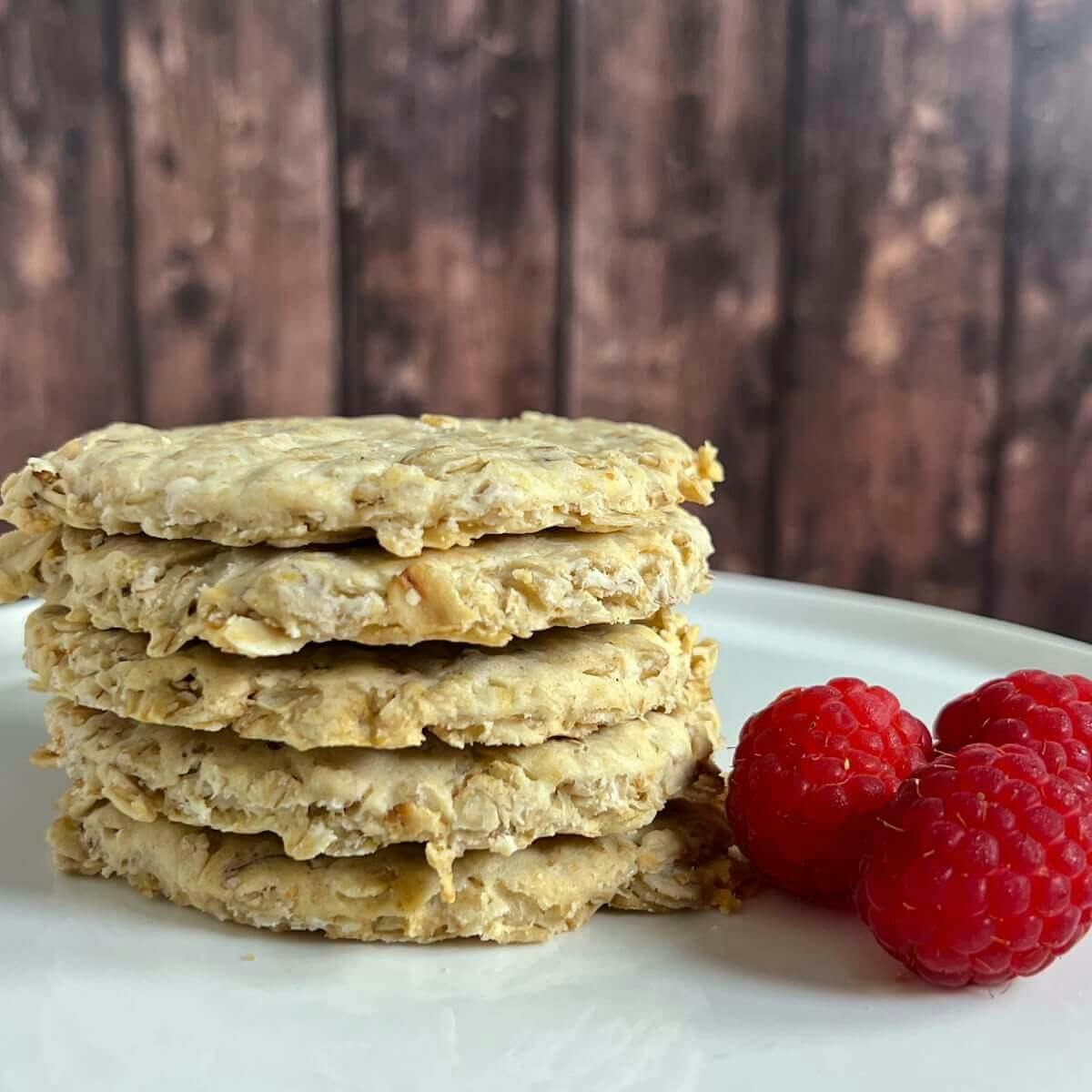 Bannocks stacked on a white plate with raspberries.