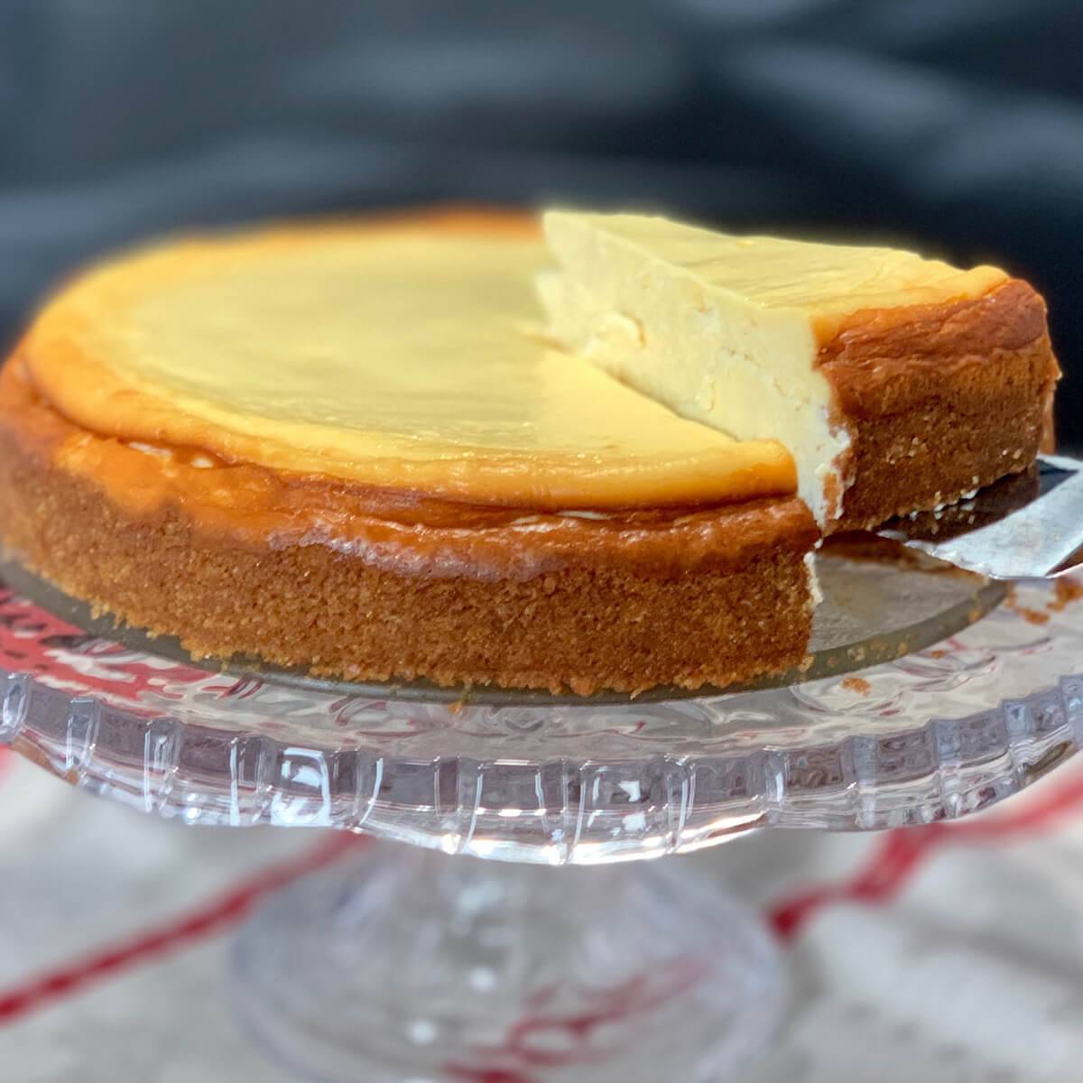White wine cheesecake on a cake plate with slice being lifted out.