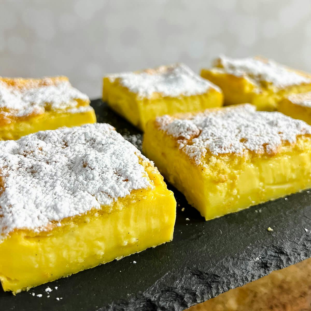 Magic Custard Cake slices on a black slate platter.