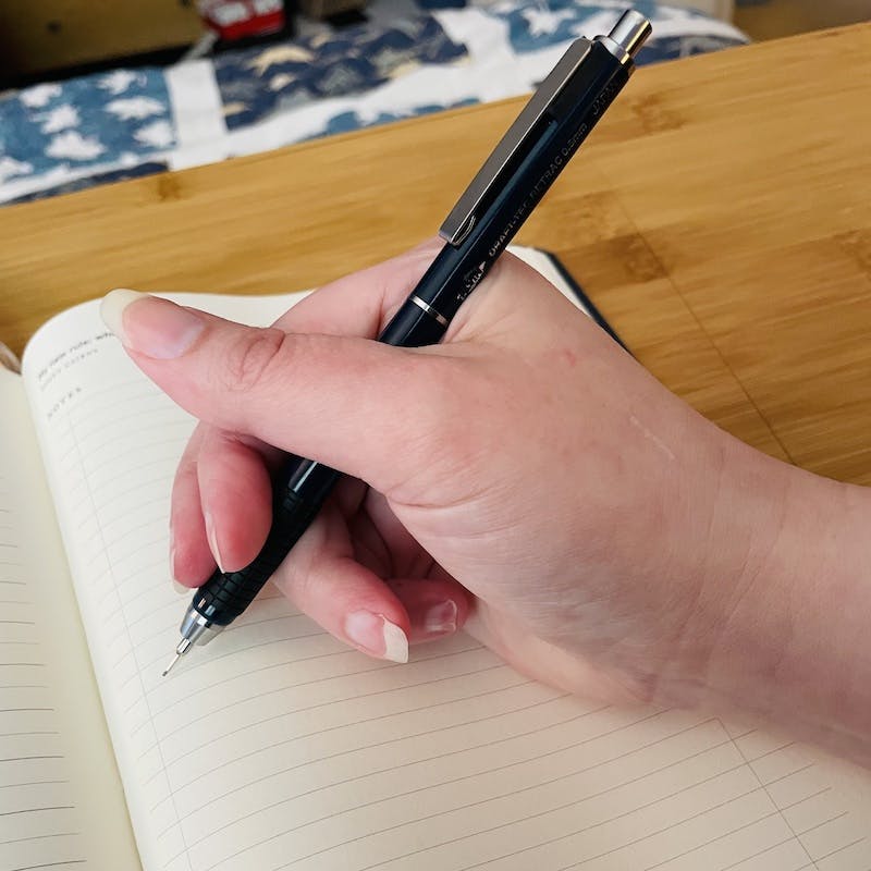 Kat Vancil’s hand holding a Alvin Draft-Tec mech pencil above a Full Focus Planner