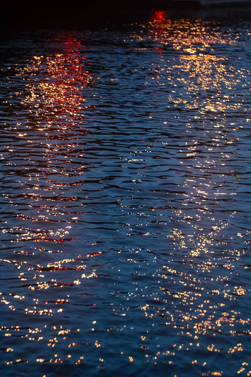 Ripples on dark water reflecting colorful lights