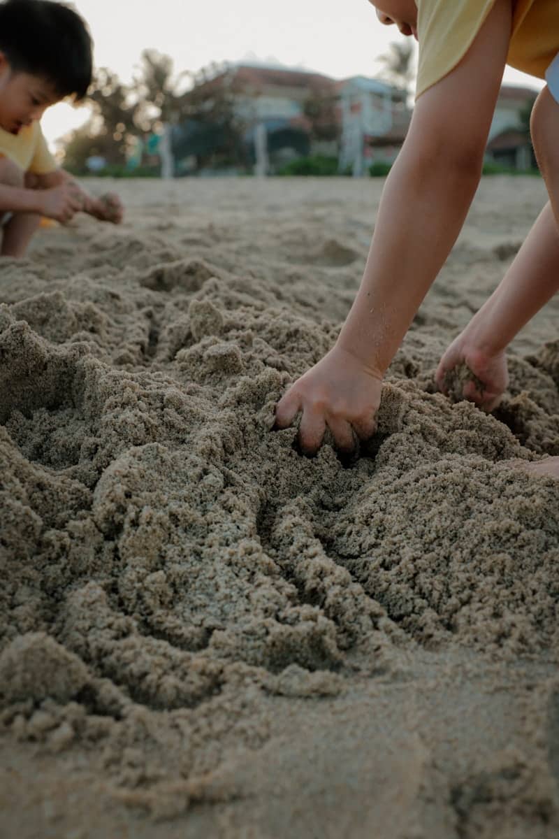 Children playing with sand on a beach.