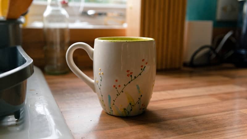 A decorated mug sits on a wooden countertop.