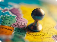 A colorful red, orange, pink and yellow image of a world map and a metal piece over Nigeria 