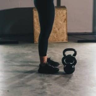 woman in black tank top and black leggings standing on white floor