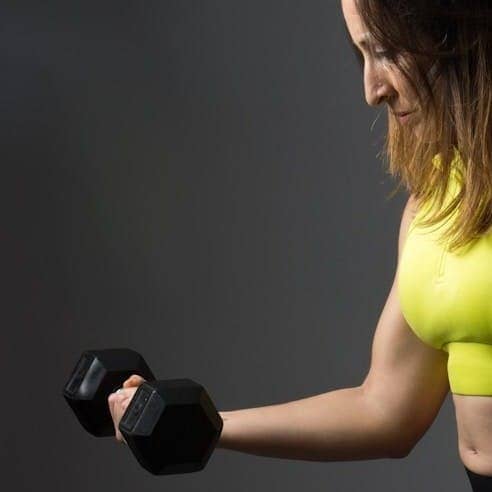 woman wearing pink sports bra holding dumbbells