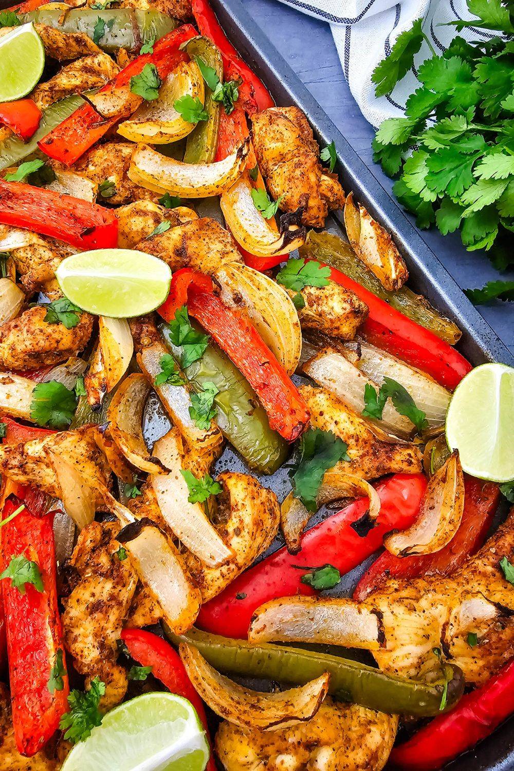 A close up of sheet pan with baked chicken and peppers