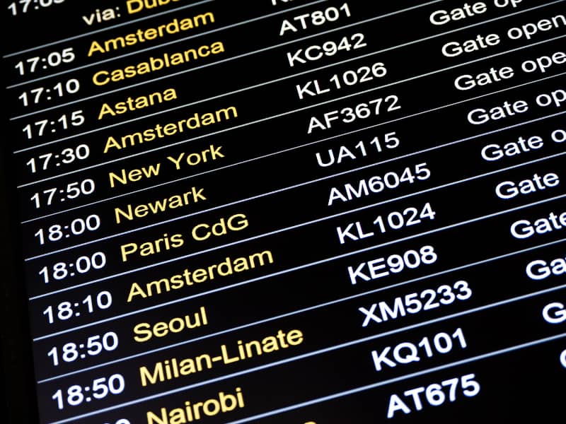 An airport departure board listing various destinations and times. 