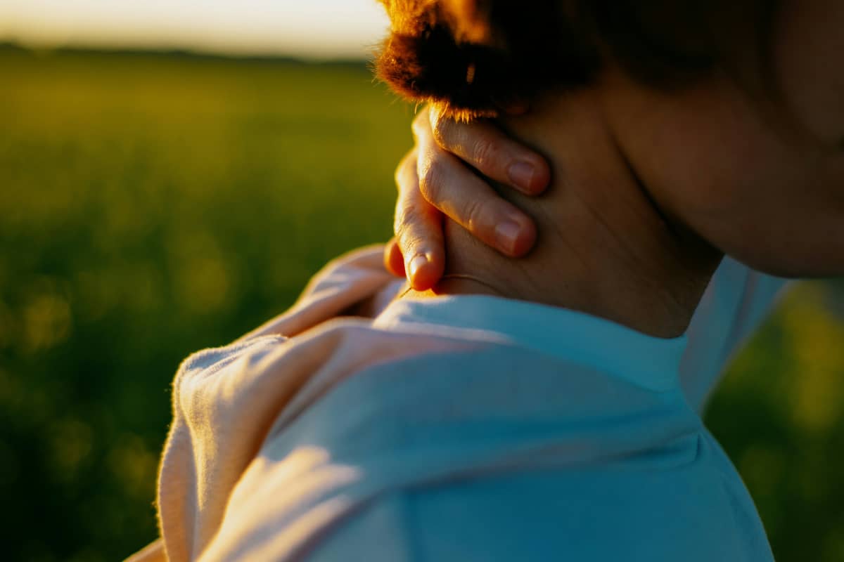 woman with hand on neck reflecting the experience of neck and shoulder pain