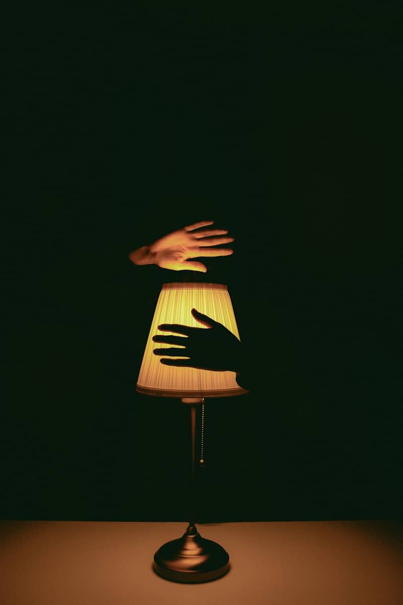 A hand reaching for a lamp shade on a table