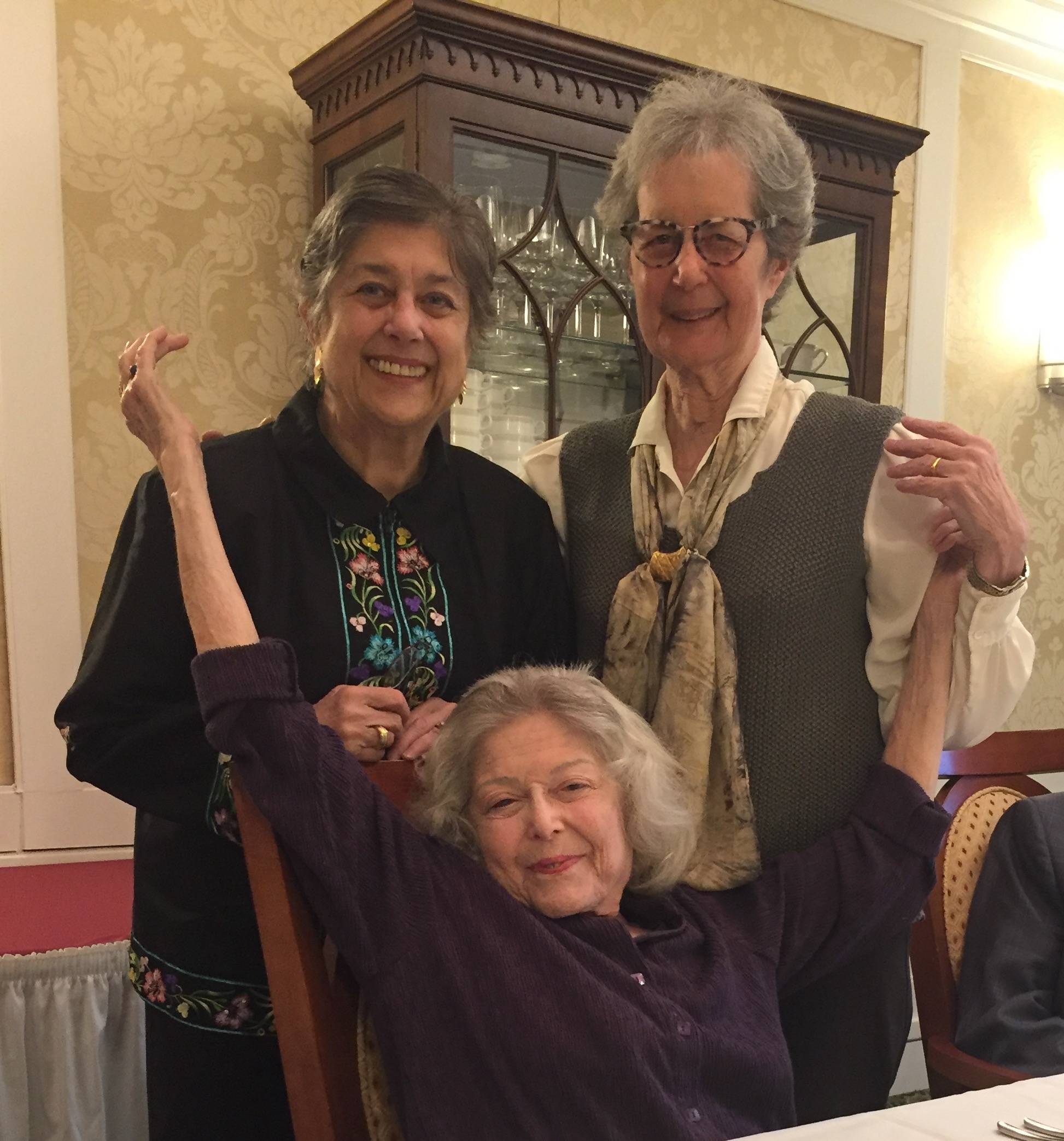 The three Friedman sisters together, smiling and laughing at a family gathering. My Aunt Joan ("Aunt Mommy") stands on the right, my mom stands on the left, and their oldest sister sits in front with her arms triumphantly raised.