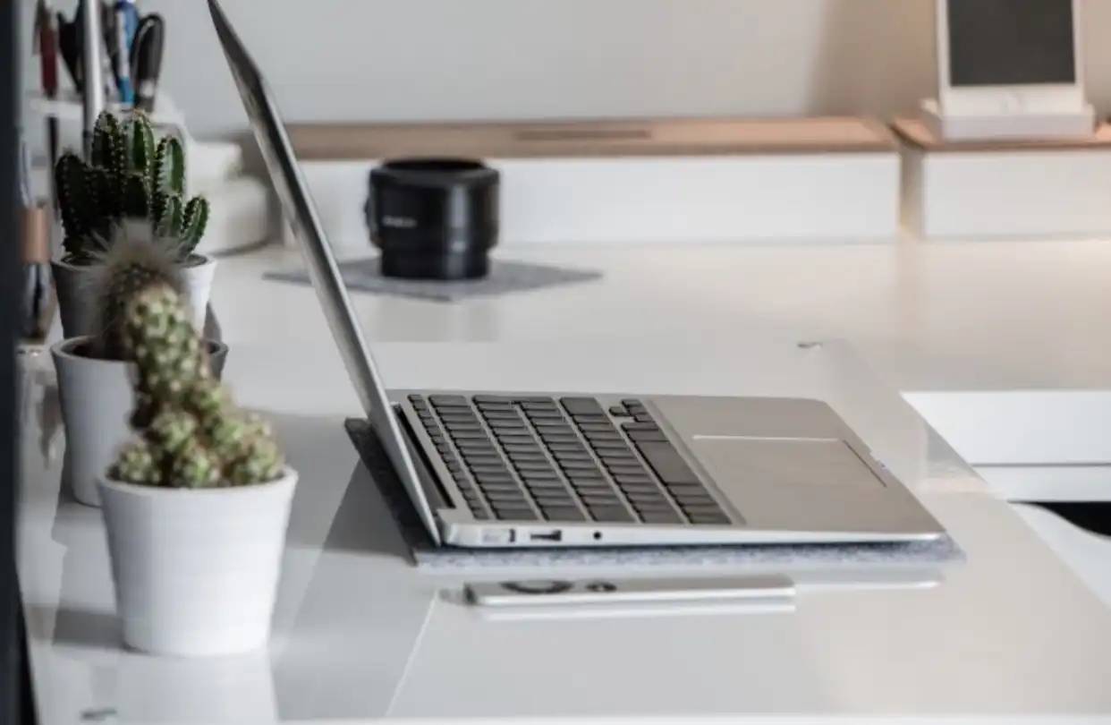 A laptop on the table with a cup and some notes arround