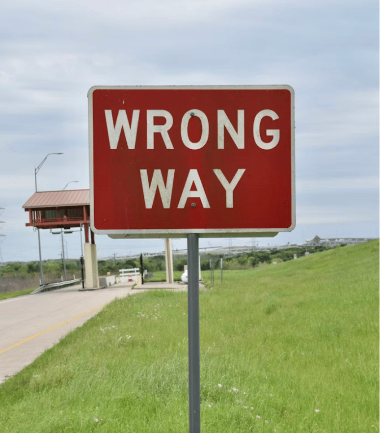 Red and white Wrong Way sign on a roadside