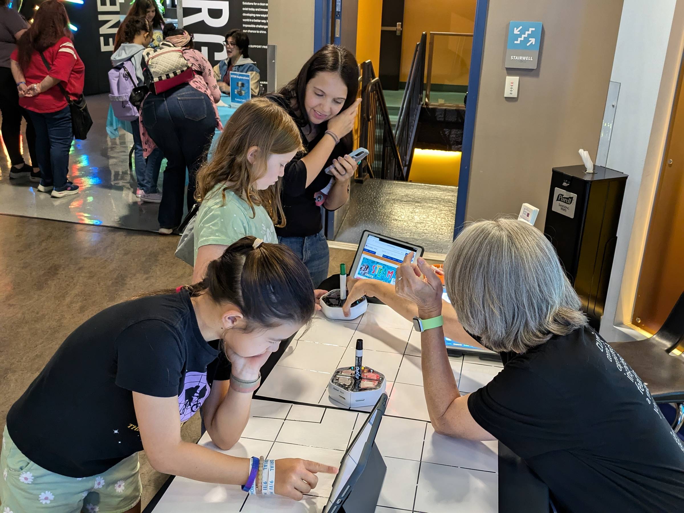 Woman talks with young girls at a robotics booth