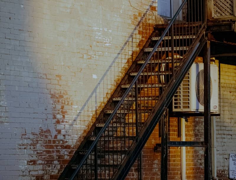 Rusty metal stairs against a brick wall
