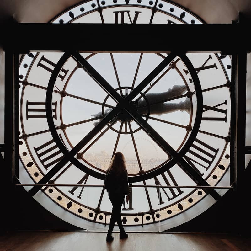 a woman standing in front of a clock intending that time slows down