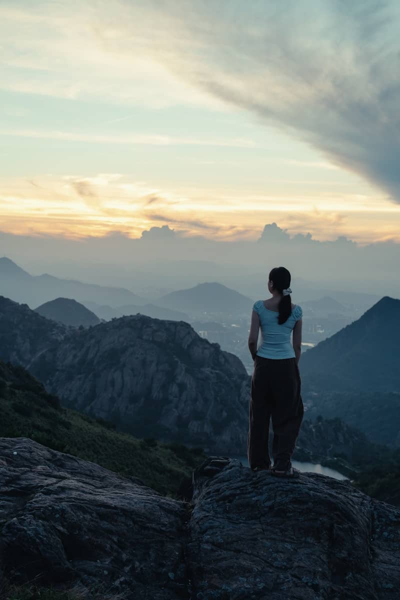 Woman overlooks a vast mountain range at sunset.