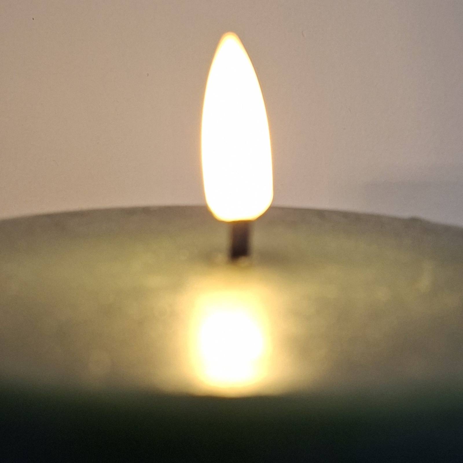 A green candle with a flame lighting. We all deserve the twentieth night.