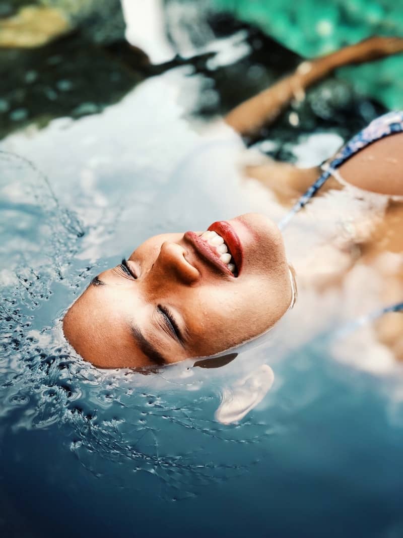 A woman submerged in water with only her face showing. 