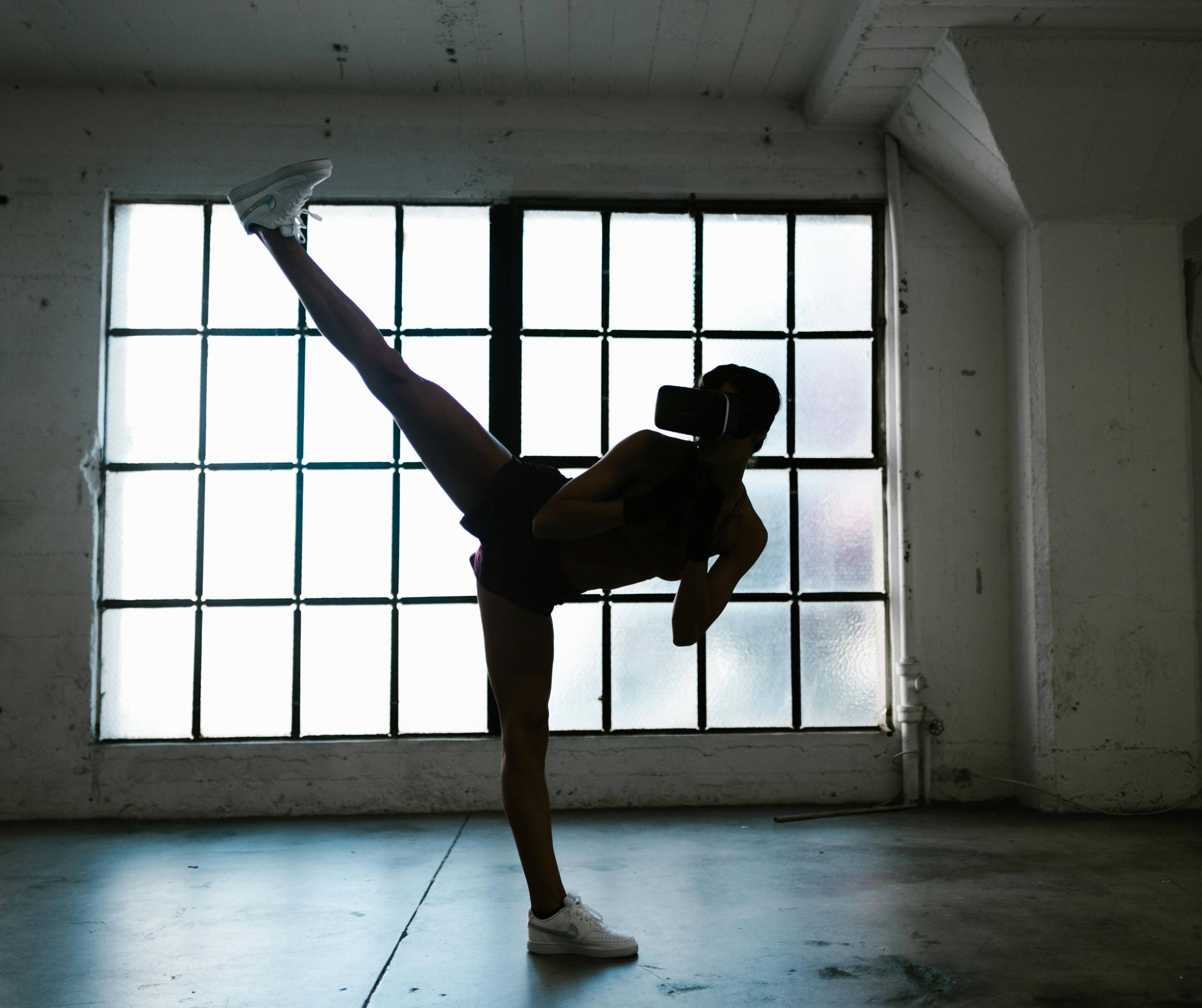 Silhouette of a person kickboxing against a dimly lit background.