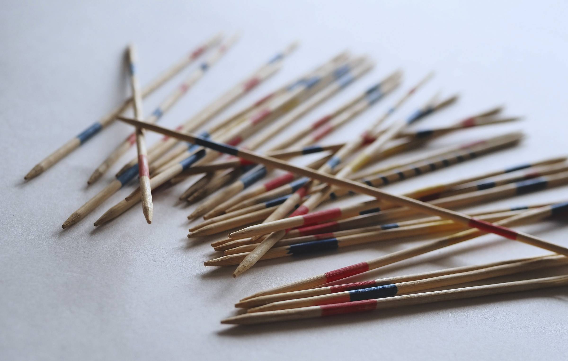 Scattered pick-up sticks in a loose pile, with one stick balanced across the top on a light background.