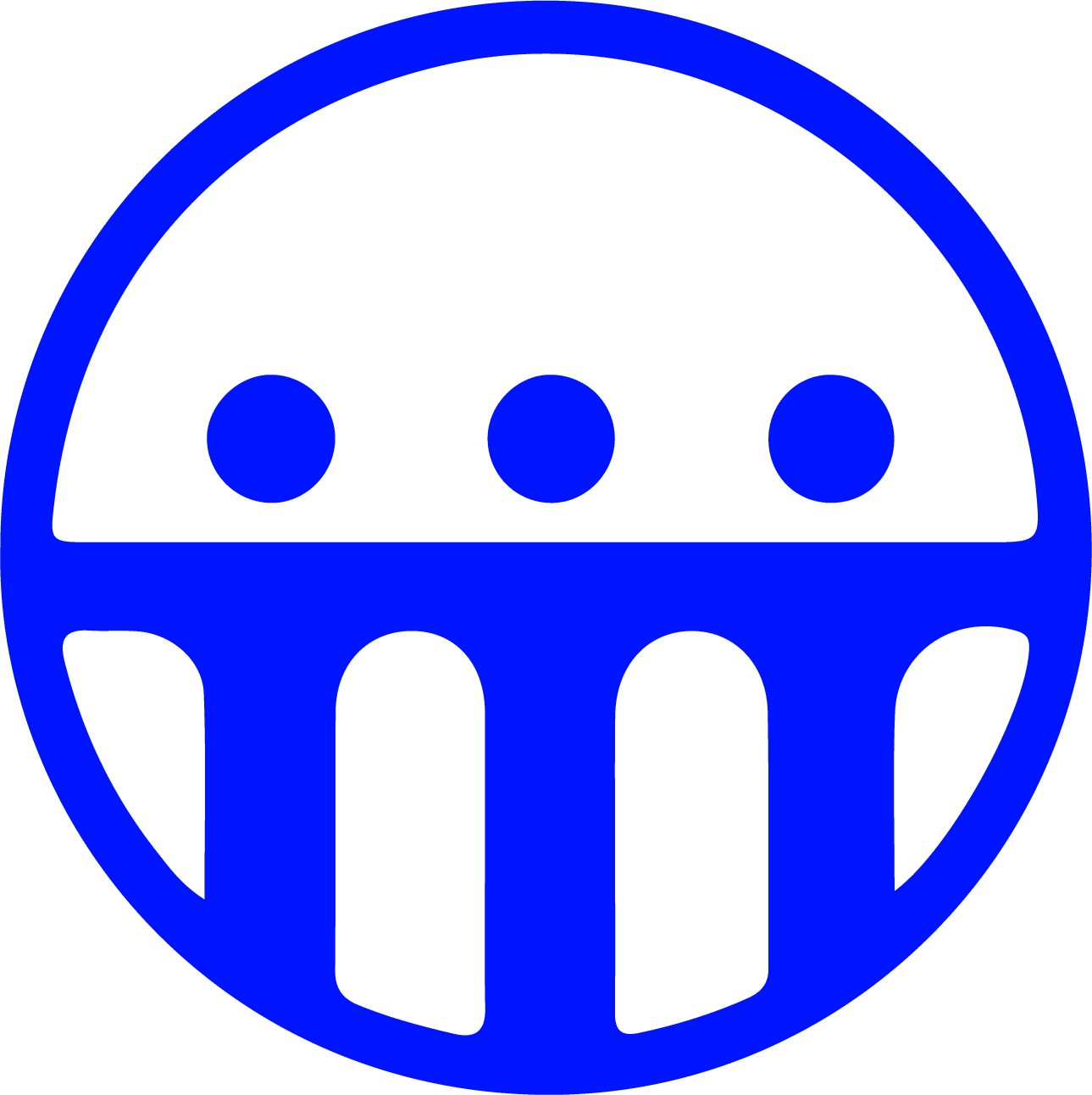 A person wearing glasses and a blue shirt is smiling, sitting indoors with a blurred background featuring warm lighting.