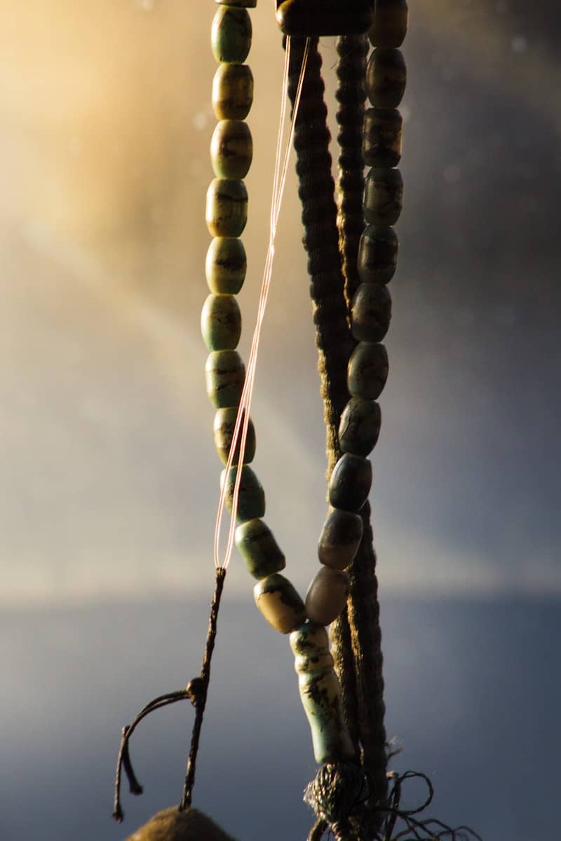 Hanging earthy-toned beads against a soft, bright background.