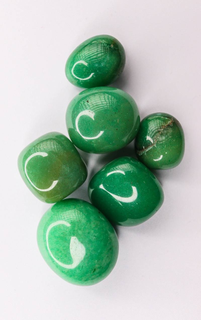 Smooth green polished stones on white.
